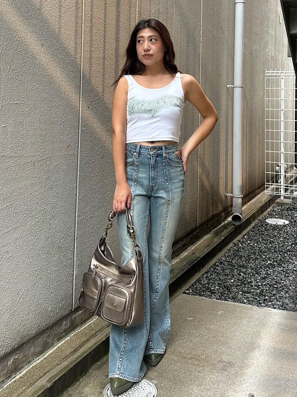 ブルー系のデニムパンツ、ゴールド系のハンドバッグ、ホワイト系のタンクトップを着用したレディースの夏コーディネートの1枚目の写真