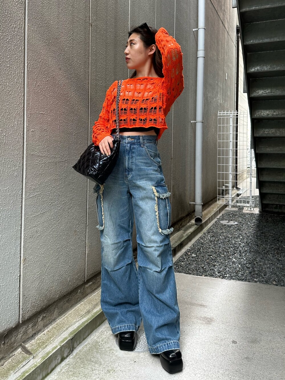 ブラック系のショルダーバッグ、ブラック系のサンダル、ブルー系のデニムパンツを着用したレディースの春コーディネートの1枚目の写真