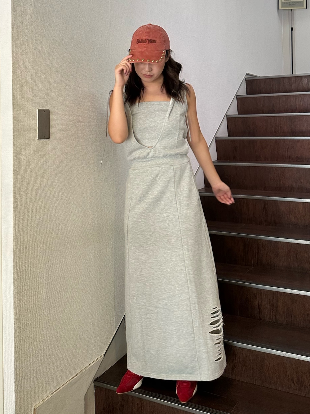 グレー系のワンピース、レッド系のパンプス、レッド系のキャップを着用したレディースの夏コーディネートの1枚目の写真