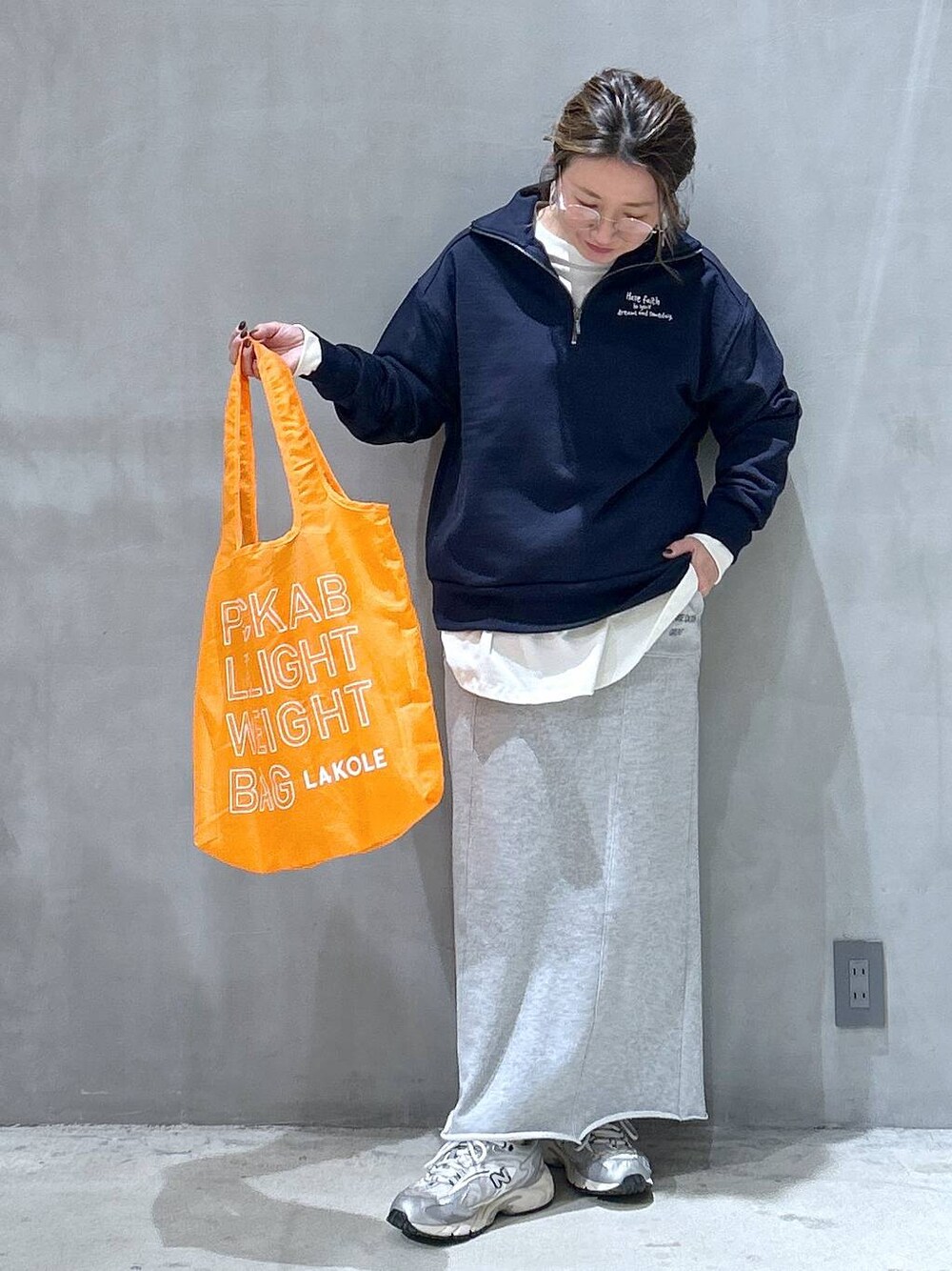 オレンジ系のエコバッグ/サブバッグ、ブルー系のスウェット、グレー系のスカートを着用したレディースの冬コーディネートの1枚目の写真
