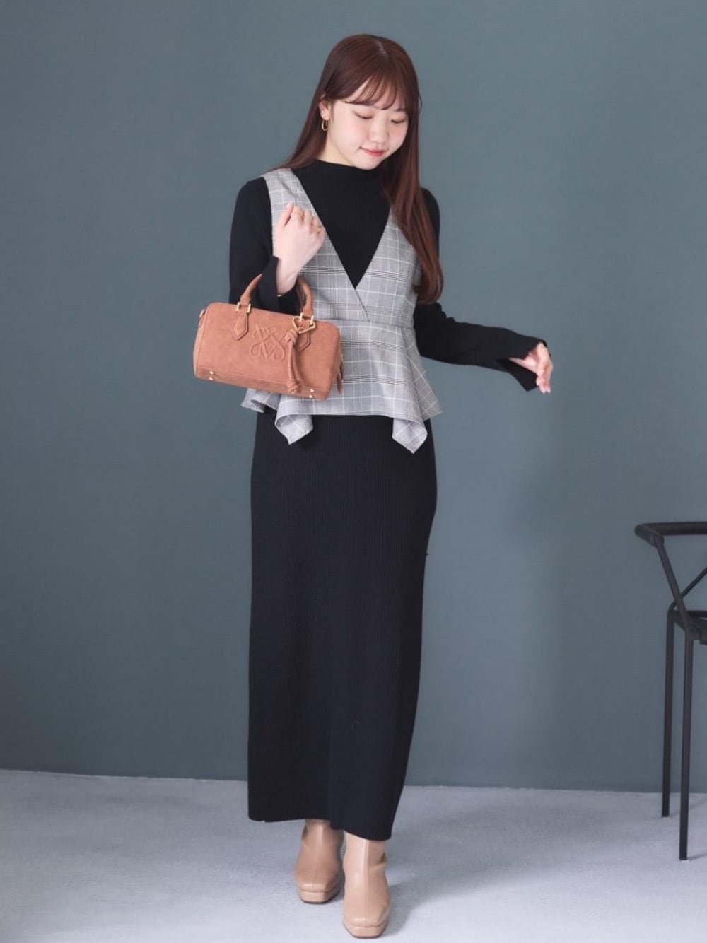 ホワイト系のキャミソール、ブラウン系のボストンバッグ、ベージュ系のブーツを着用したレディースの秋コーディネートの1枚目の写真