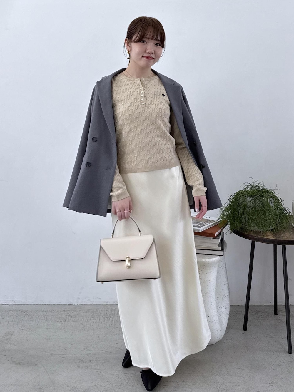 グレー系のテーラードジャケット、ブラック系のブーツ、ホワイト系のスカートを着用したレディースの秋コーディネートの1枚目の写真