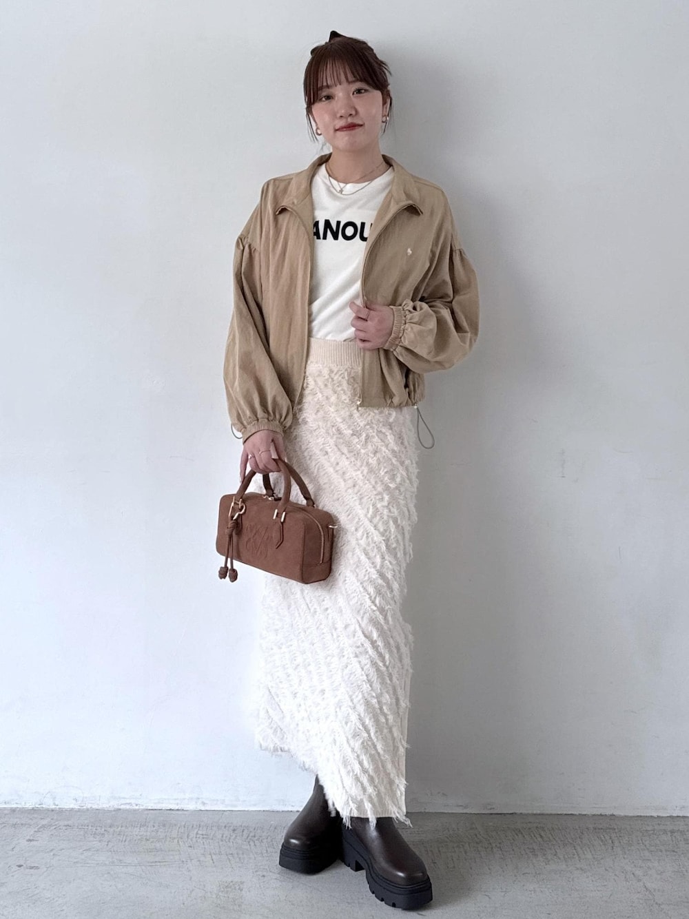 ブラウン系のボストンバッグ、ホワイト系のTシャツ/カットソー、ベージュ系のブルゾンを着用したレディースの秋コーディネートの1枚目の写真