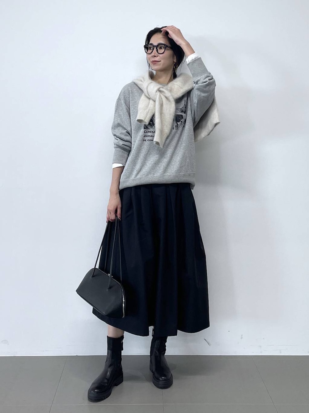 ブラック系のトートバッグ、ブラック系のブーツ、ホワイト系のTシャツ/カットソーを着用したレディースの秋コーディネートの1枚目の写真
