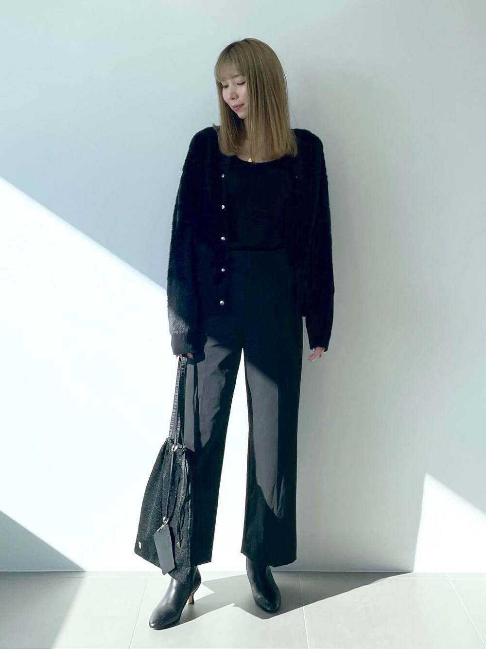 ブラック系のタンクトップ、ブラック系のブーツ、ブラック系のトートバッグを着用したレディースの冬コーディネートの1枚目の写真