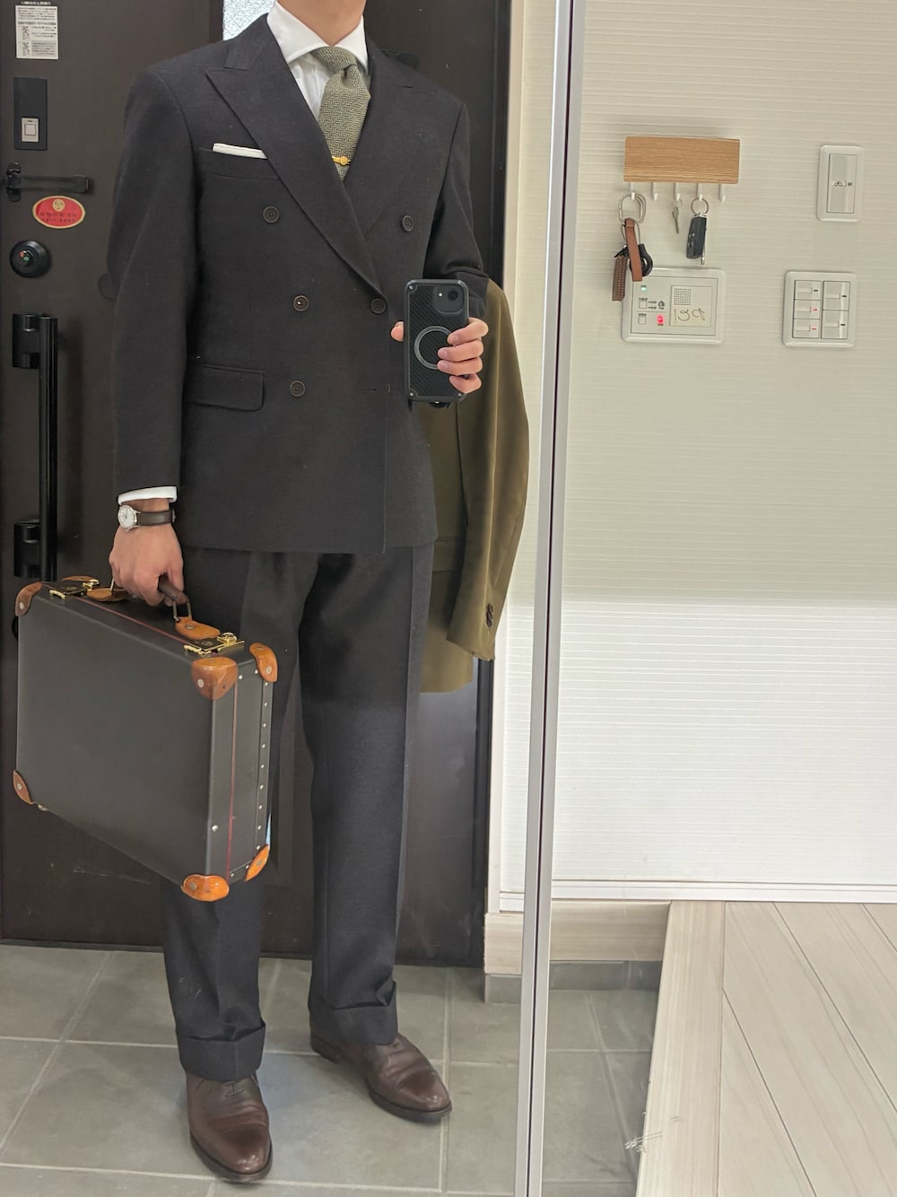 ホワイト系のビジネスシャツ、ゴールド系のネクタイピン、ブラウン系のテーラードジャケットを着用したメンズの冬コーディネートの1枚目の写真