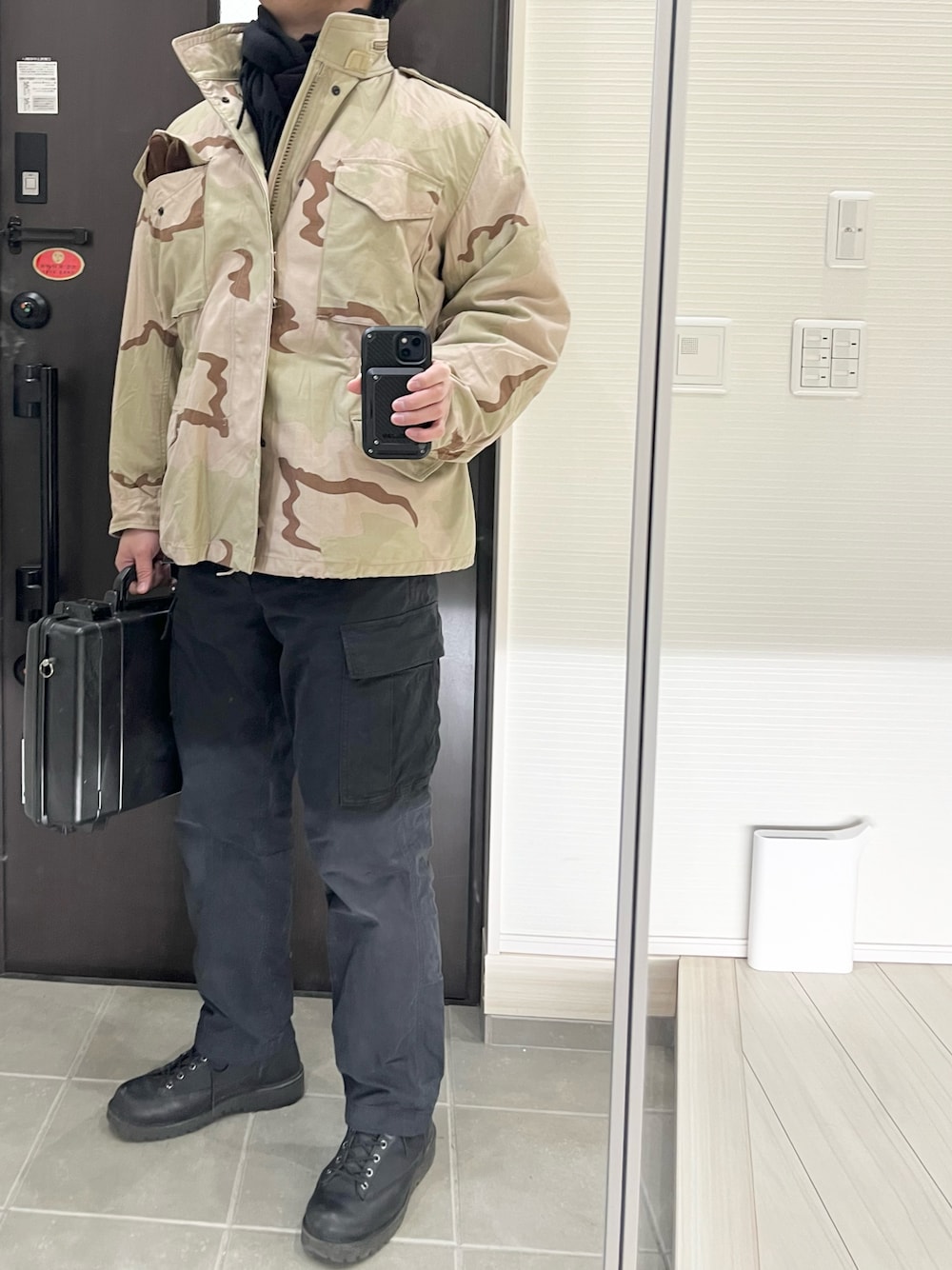 ブラック系のカーゴパンツ、ブラック系のブーツ、ブラック系のバッグを着用したメンズの春コーディネートの1枚目の写真