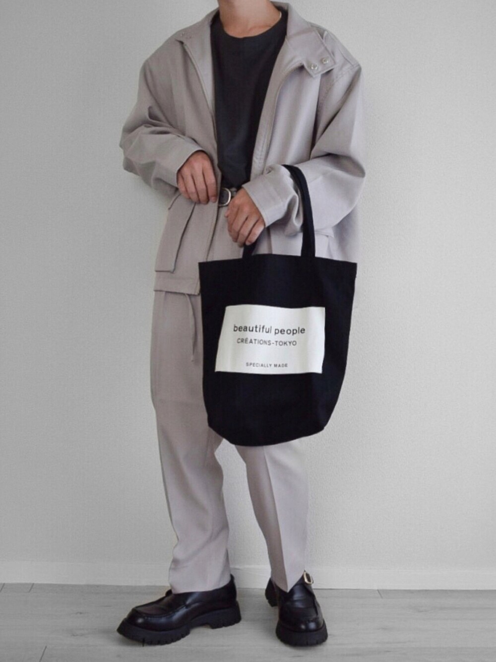 ベージュ系のブルゾン、ベージュ系のスラックス、ブラック系のTシャツ/カットソーを着用したメンズの秋コーディネートの1枚目の写真