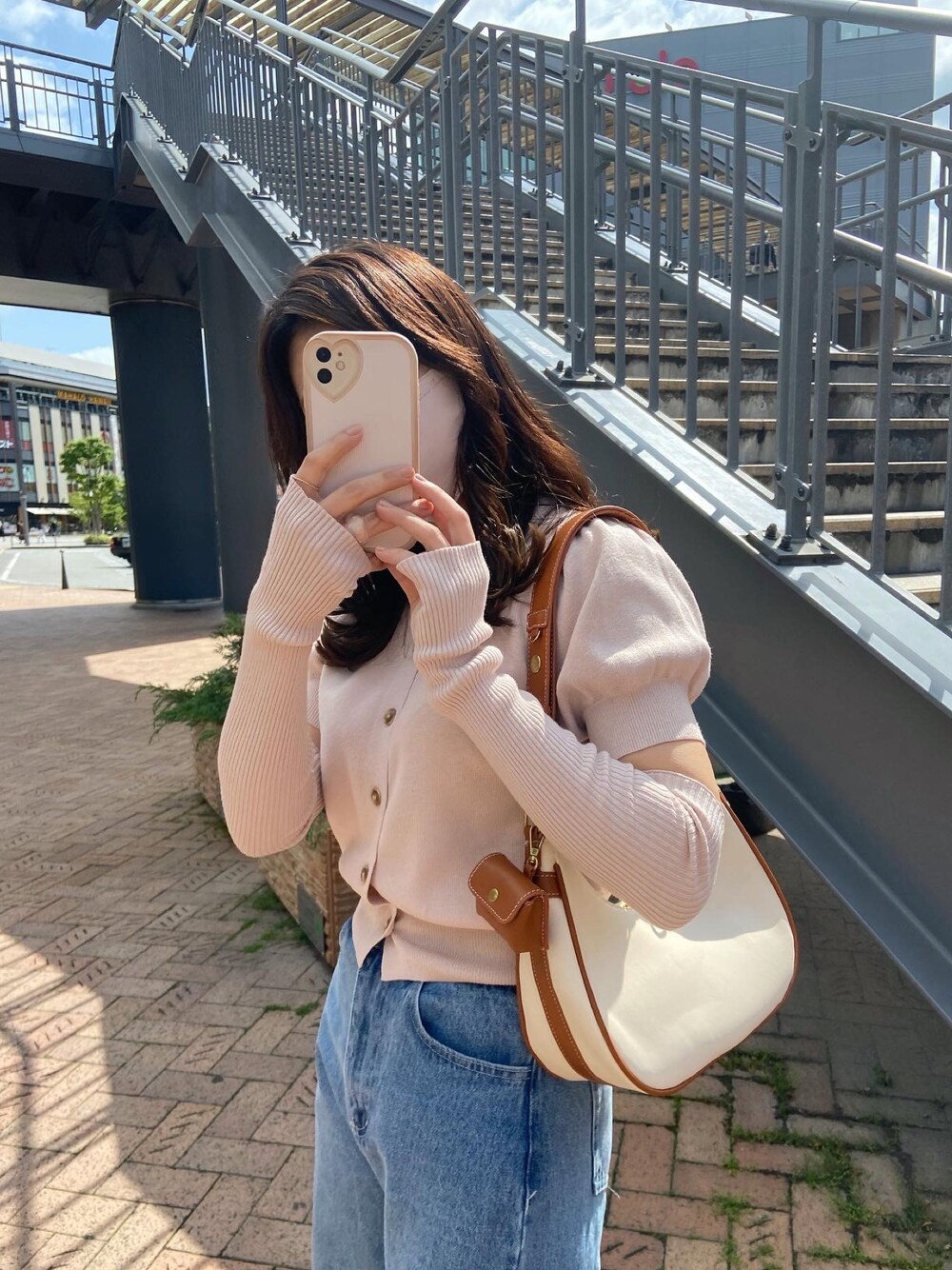 ピンク系のニット/セーター、ブルー系のデニムパンツ、ホワイト系のショルダーバッグを着用したレディースの春コーディネートの1枚目の写真