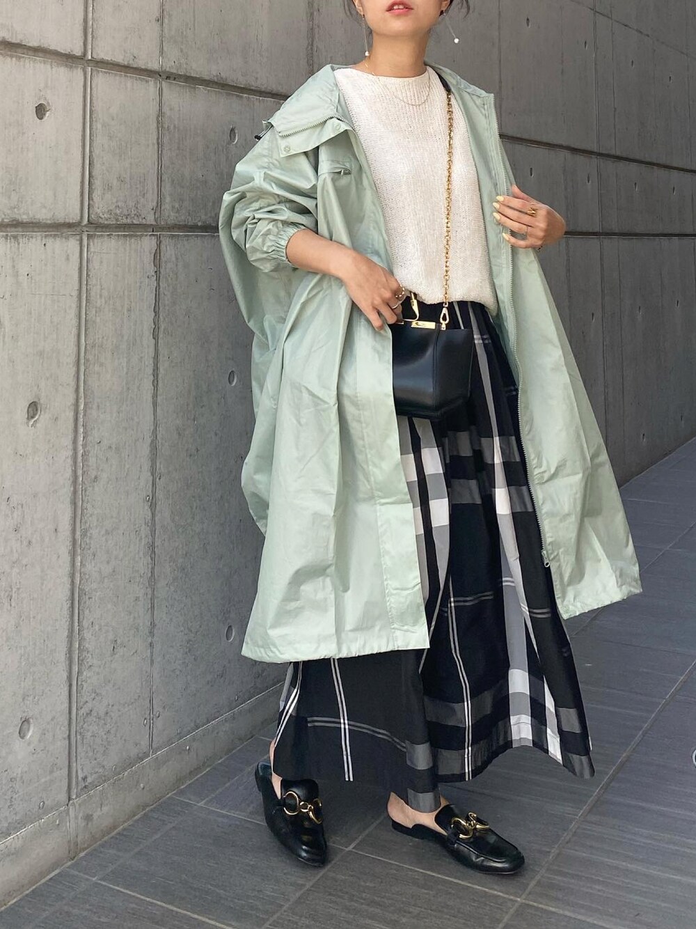 ブラック系のハンドバッグ、ブラック系のスカート、ブラック系のシューズを着用したレディースの春コーディネートの1枚目の写真