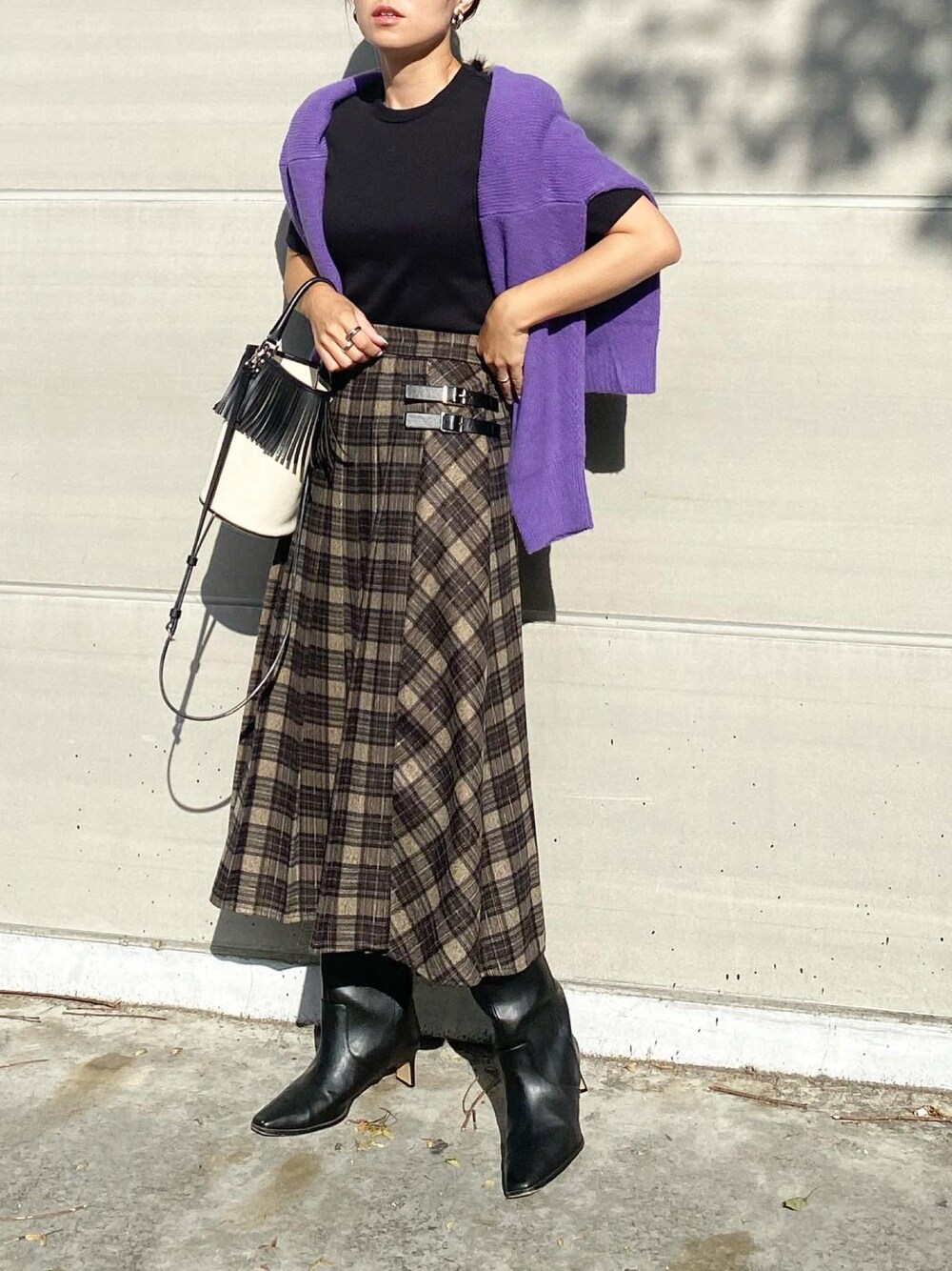 グレー系のスカート、ブラック系のブーツ、ホワイト系のバッグを着用したレディースの秋コーディネートの1枚目の写真