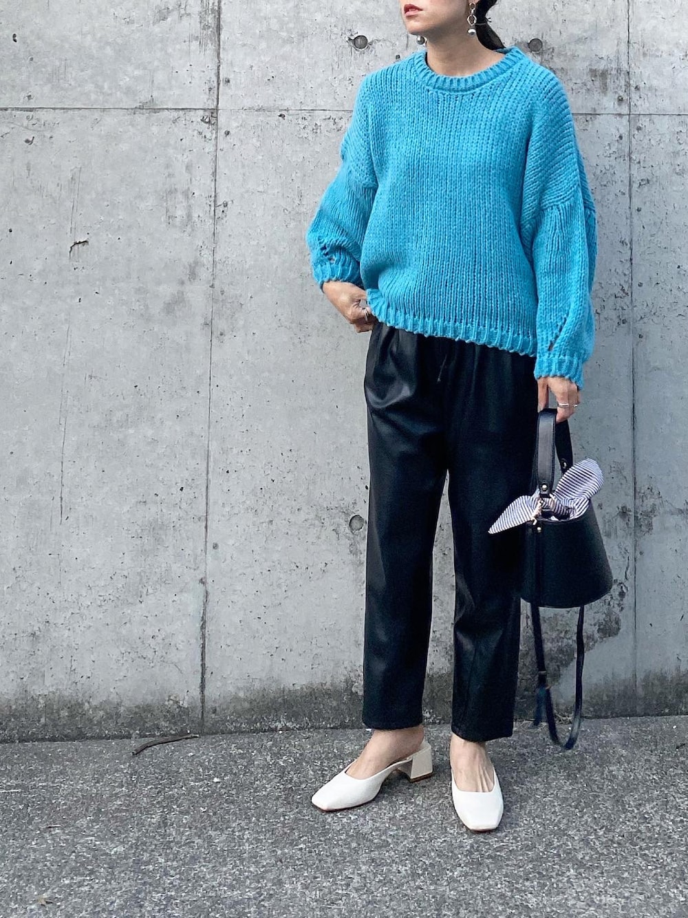 ブラック系のパンツ、ブルー系のニット/セーター、ホワイト系のシューズを着用したレディースの秋コーディネートの1枚目の写真