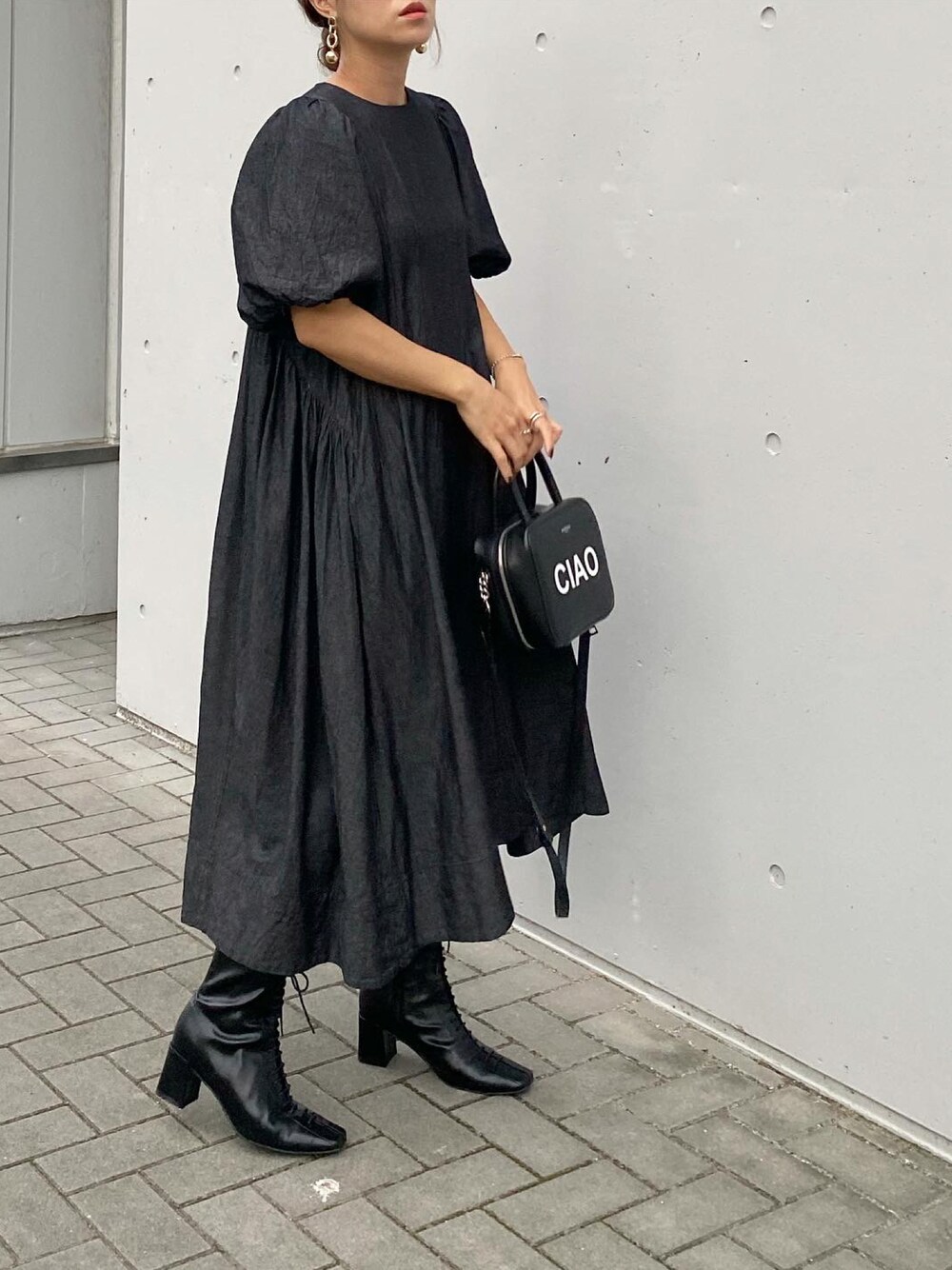 ブラック系のブーツ、ブラック系のバッグ、ブラック系のワンピース/ドレスを着用したレディースの秋コーディネートの1枚目の写真