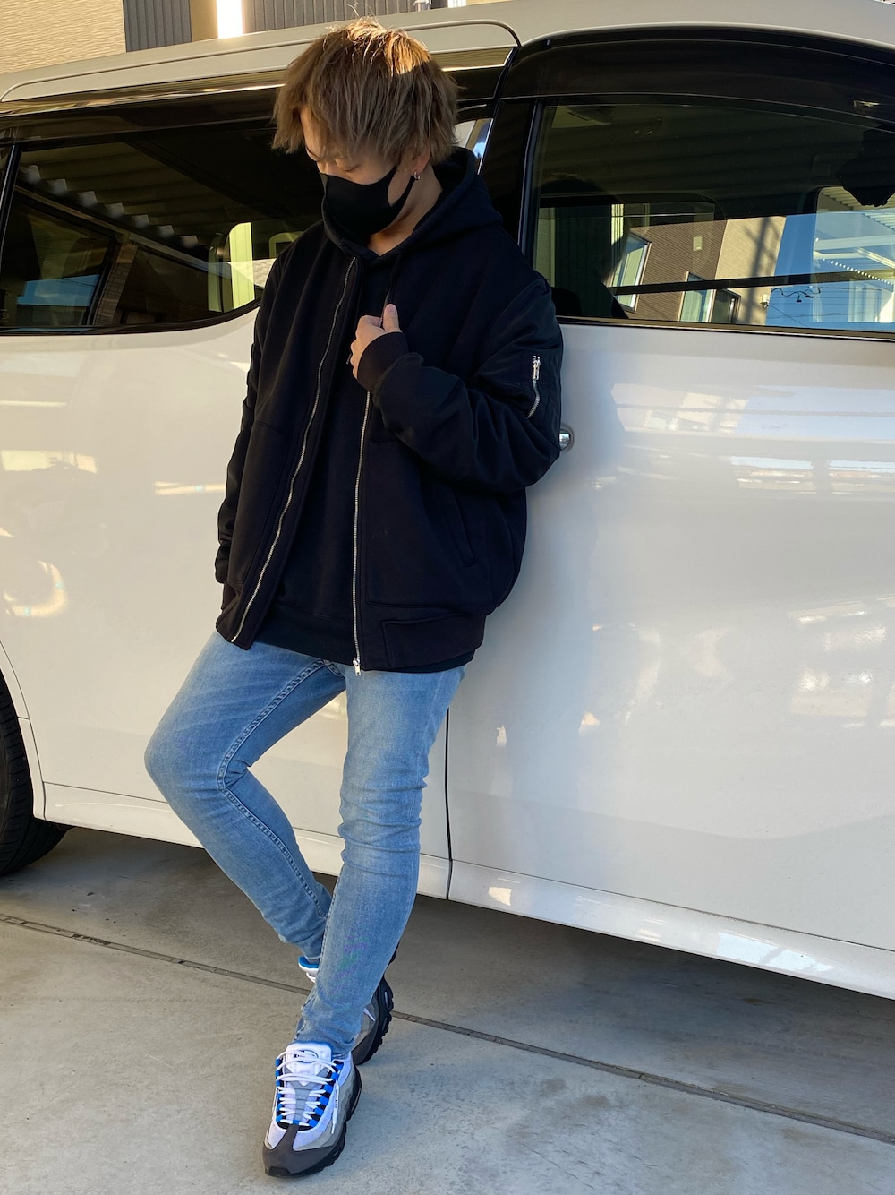 グレー系のスニーカー、ブルー系のデニムパンツ、ブラック系のパーカーを着用したメンズの秋コーディネートの1枚目の写真