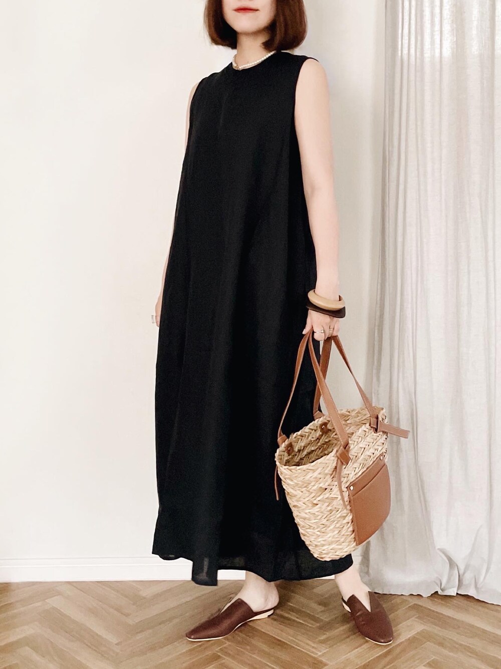 ブラック系のドレス、ブラウン系のかごバッグを着用したレディースの夏コーディネートの1枚目の写真