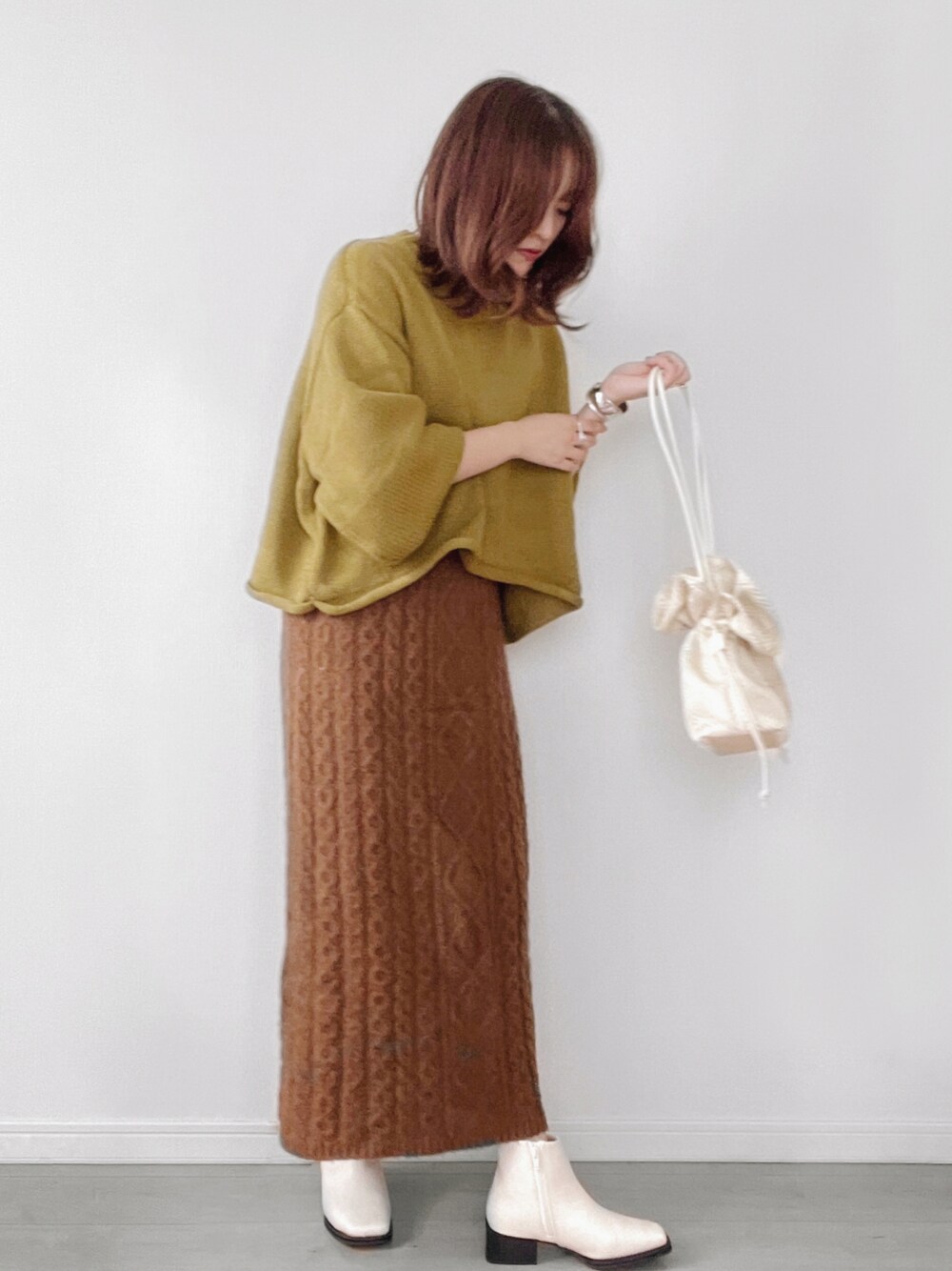 グリーン系のニット/セーター、ホワイト系のショルダーバッグを着用したレディースの秋コーディネートの1枚目の写真