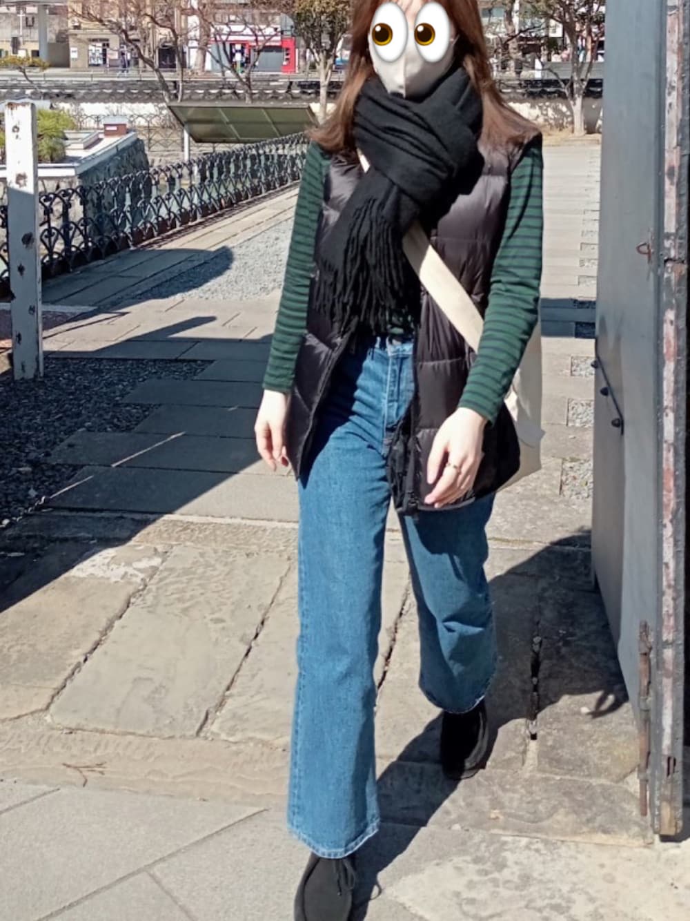 ブルー系のデニムパンツ、ブラック系のダウンベスト、グリーン系のTシャツ/カットソーを着用したレディースの春コーディネートの1枚目の写真