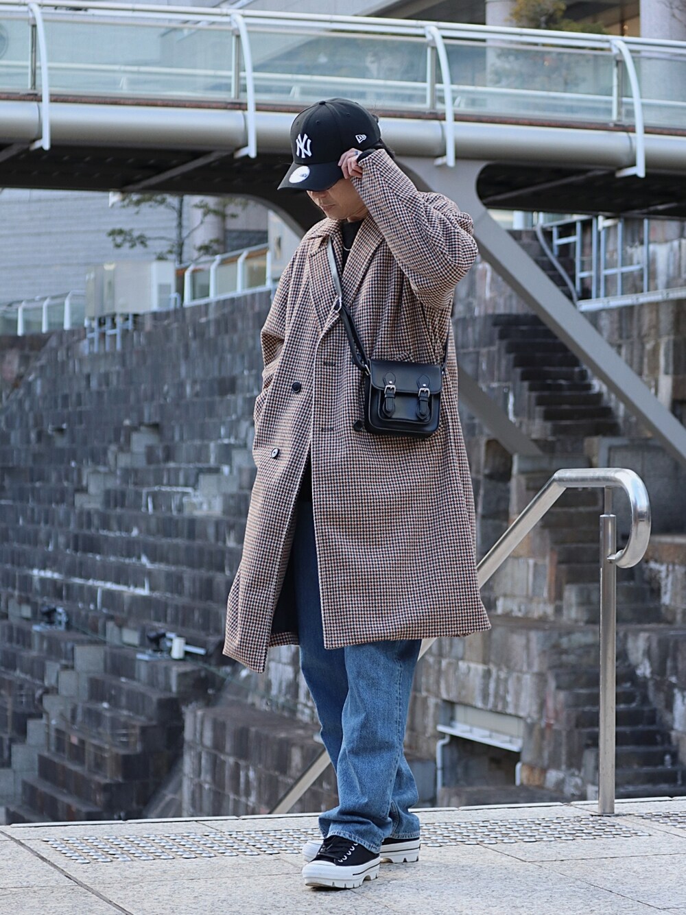 ブラック系のショルダーバッグ、ブラック系のスニーカー、ブルー系のデニムパンツを着用したメンズの冬コーディネートの3枚目の写真