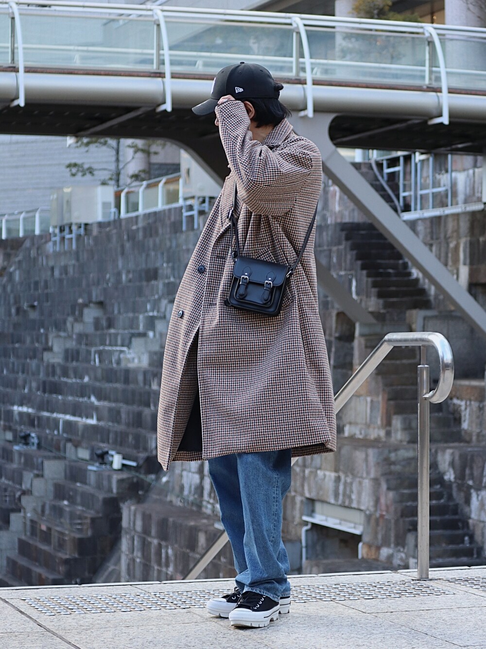 ブラック系のショルダーバッグ、ブラック系のスニーカー、ブルー系のデニムパンツを着用したメンズの冬コーディネートの2枚目の写真