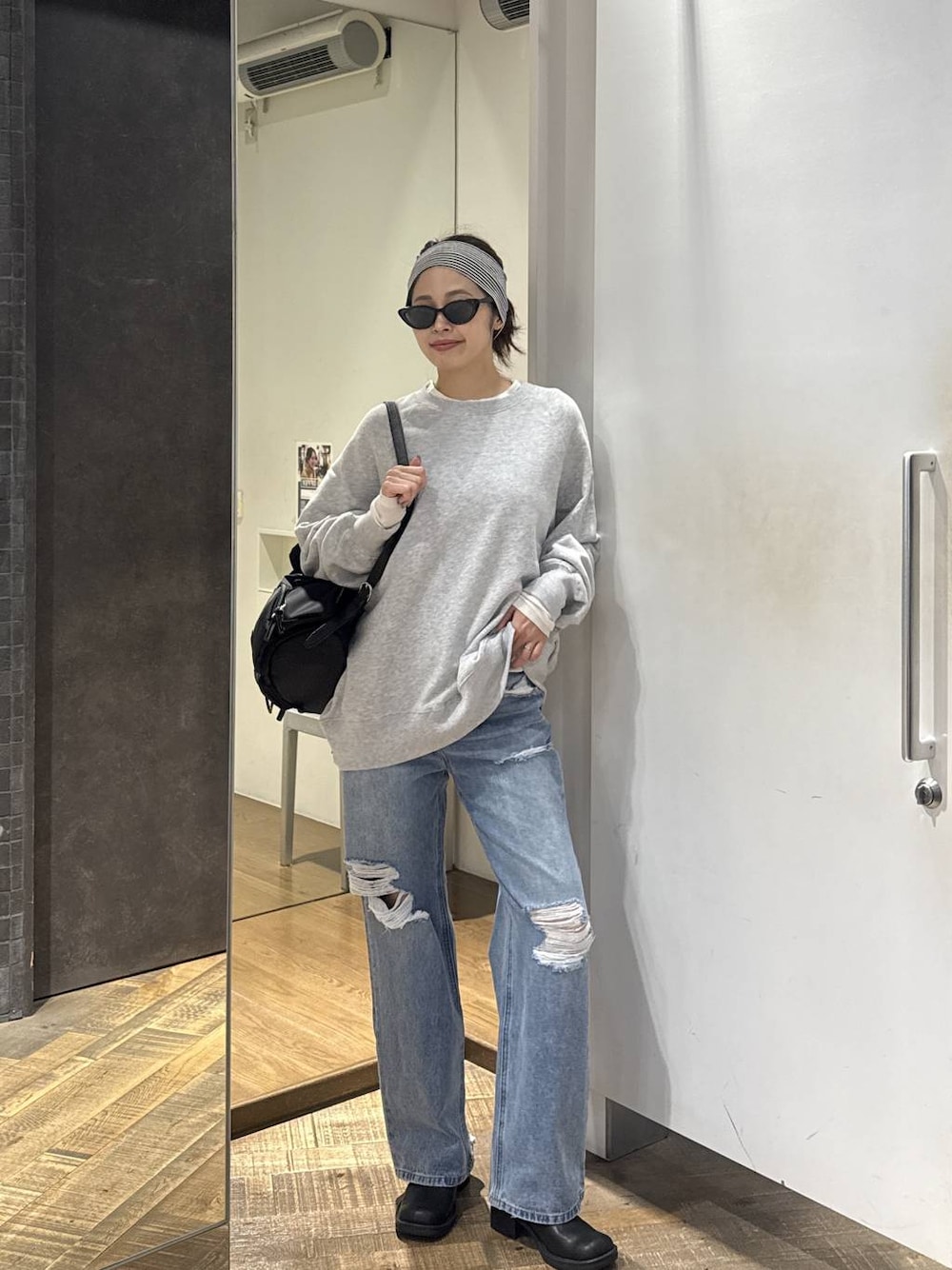 ブルー系のデニムパンツ、ブラック系のモカシン/デッキシューズ、グレー系のスウェットを着用したレディースの秋コーディネートの1枚目の写真
