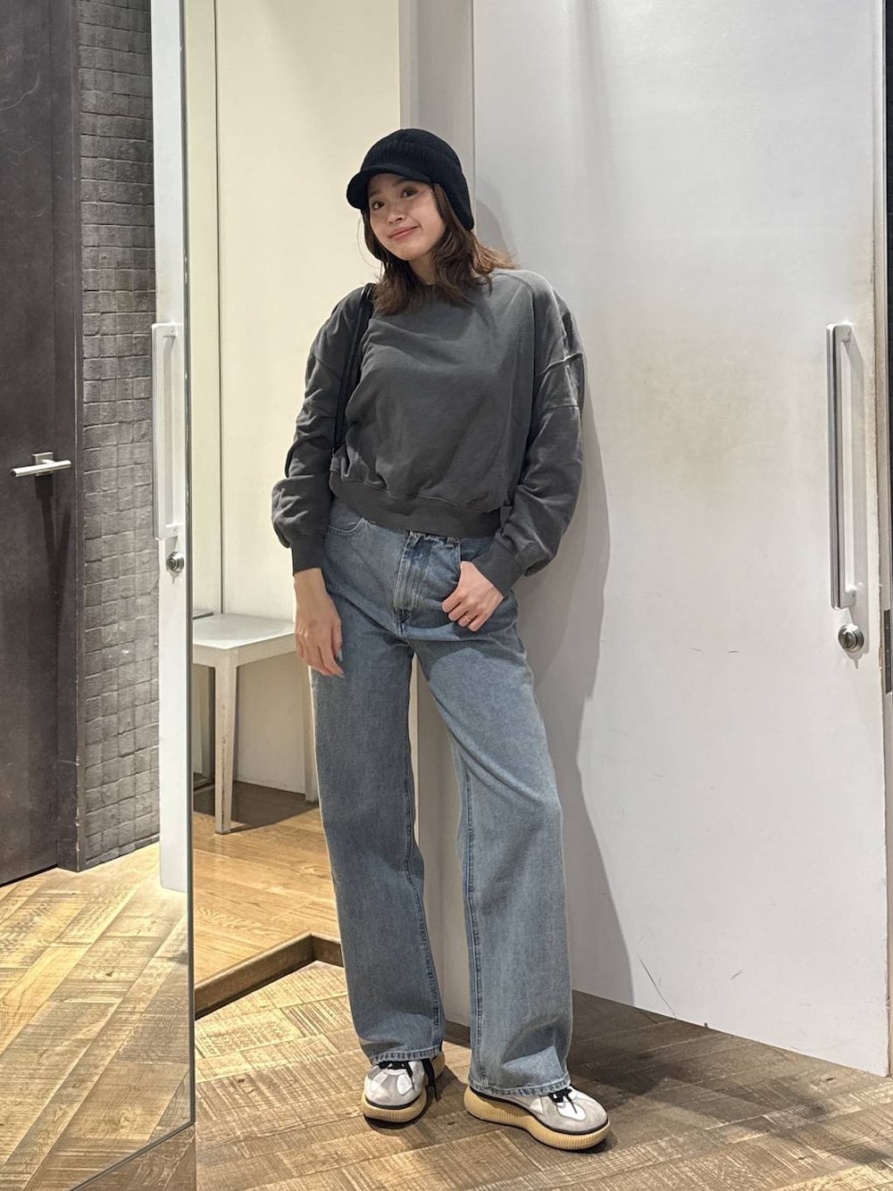 ブルー系のデニムパンツ、ブラック系のショルダーバッグ、グレー系のスウェットを着用したレディースの秋コーディネートの1枚目の写真