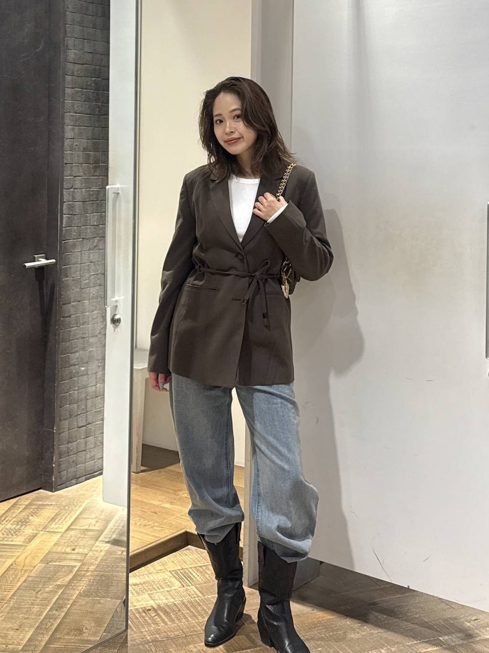 ブルー系のデニムパンツ、ブラウン系のテーラードジャケット、ホワイト系のTシャツ/カットソーを着用したレディースの秋コーディネートの1枚目の写真