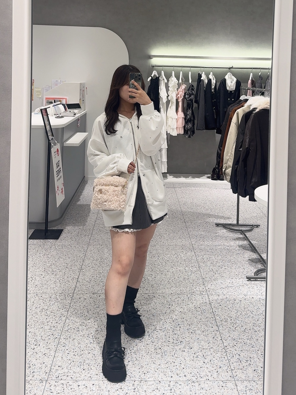 ホワイト系のパーカー、ベージュ系のショルダーバッグ、グレー系のスカートを着用したレディースの秋コーディネートの1枚目の写真