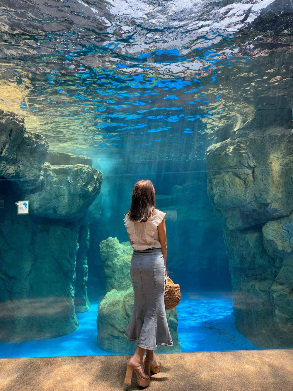 ブラック系のサンダル、ホワイト系のトップス、ブルー系のスカートを着用したレディースの夏コーディネートの1枚目の写真