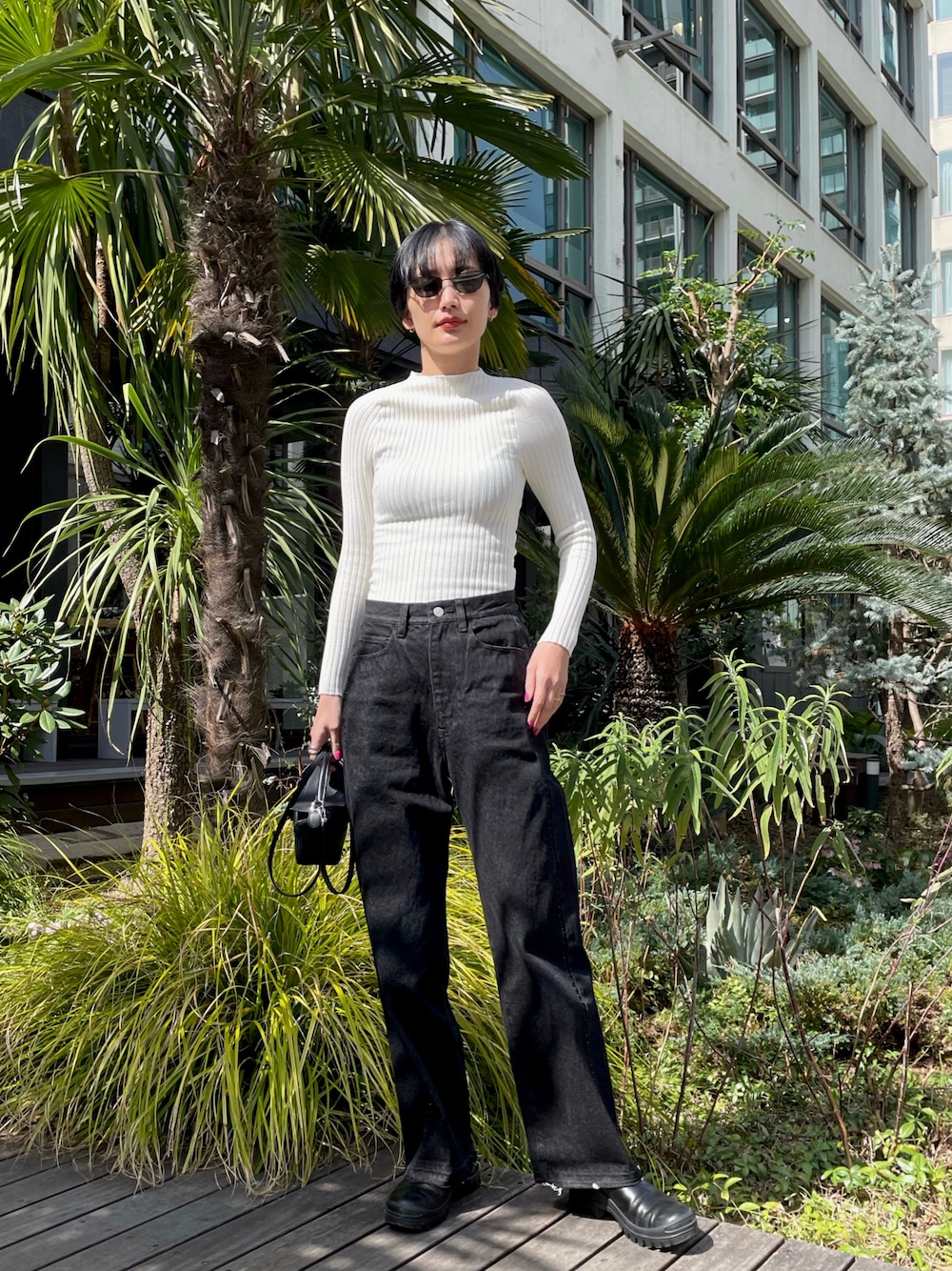 ホワイト系のトップス、ブラック系のデニムパンツ、ブラック系のハンドバッグを着用したレディースの春コーディネートの1枚目の写真