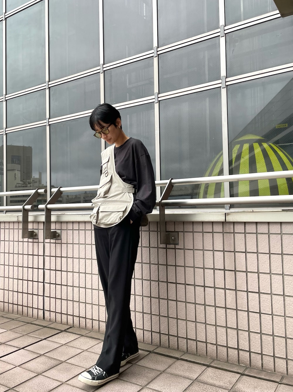 グリーン系のベスト、ブラック系のその他パンツ、ブラック系のスニーカーを着用したレディースの春コーディネートの1枚目の写真