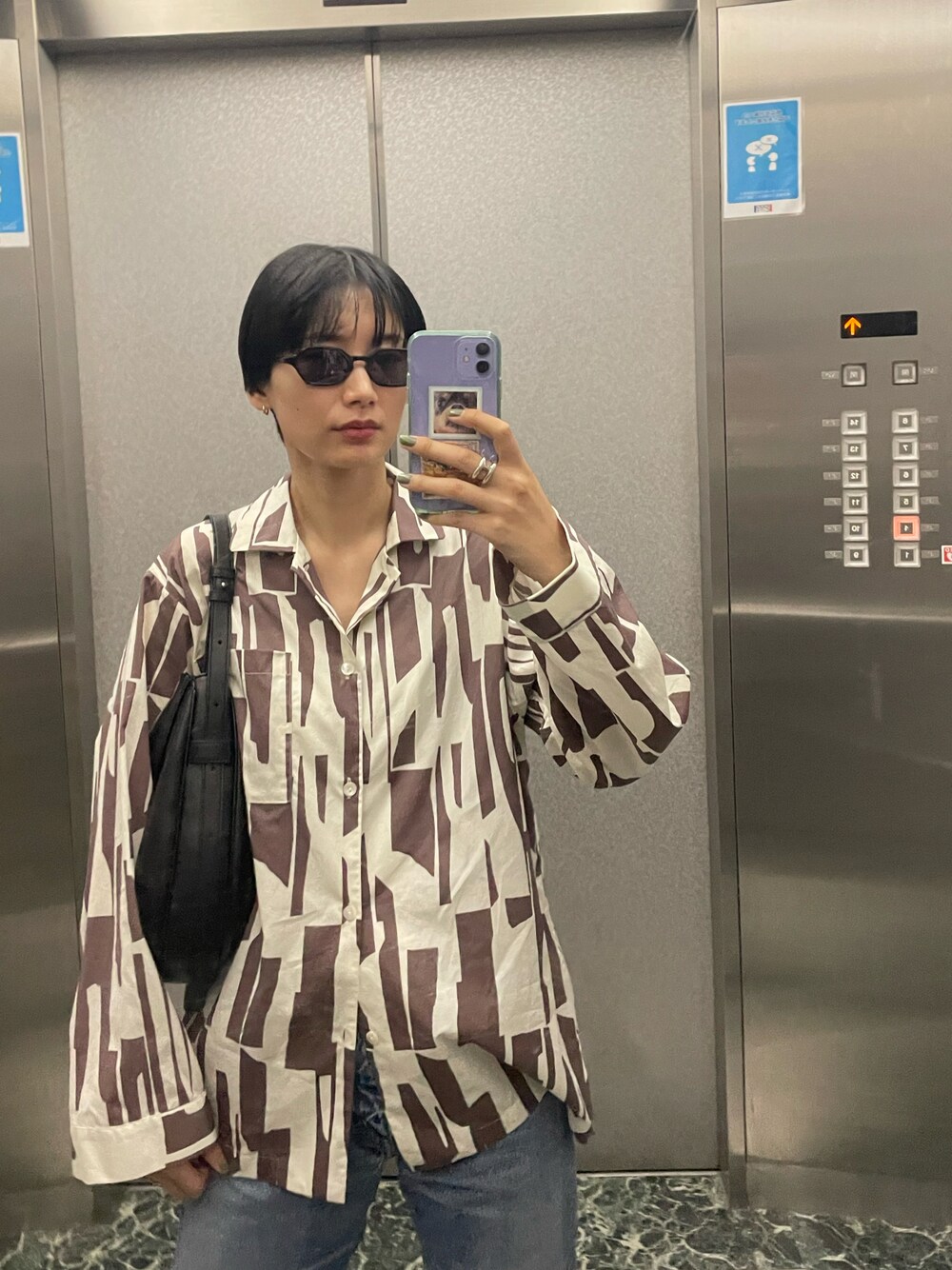 パープル系のシャツ/ブラウス、ブラック系のハンドバッグ、ブルー系のデニムパンツを着用したレディースの春コーディネートの1枚目の写真