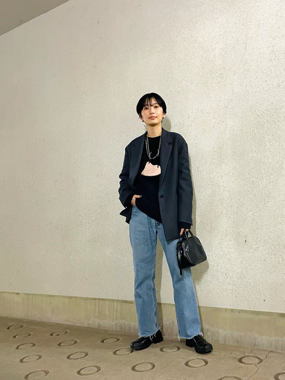 グレー系のテーラードジャケット、ブラック系のニット/セーター、ブラック系のボストンバッグを着用したレディースの春コーディネートの1枚目の写真