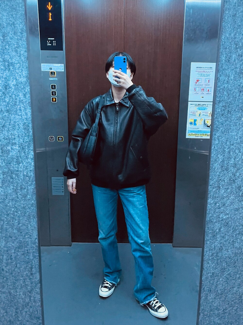 ブラック系のハンドバッグ、ブルー系のデニムパンツ、ブラック系のスニーカーを着用したレディースの春コーディネートの1枚目の写真