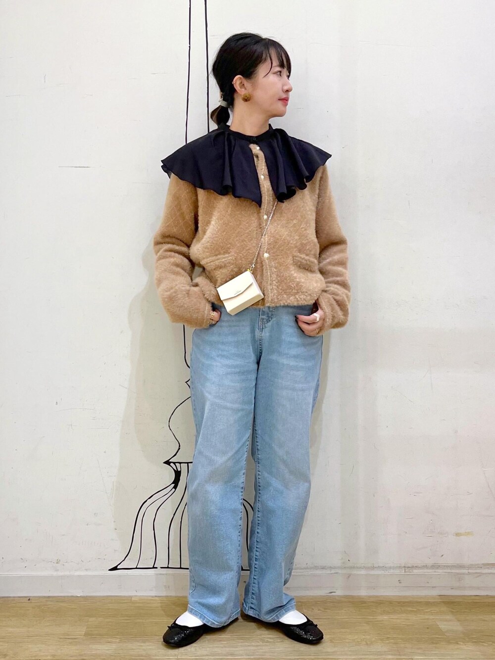 ブルー系のデニムパンツ、イエロー系のカーディガン/ボレロ、ホワイト系のショルダーバッグを着用したレディースの秋コーディネートの1枚目の写真