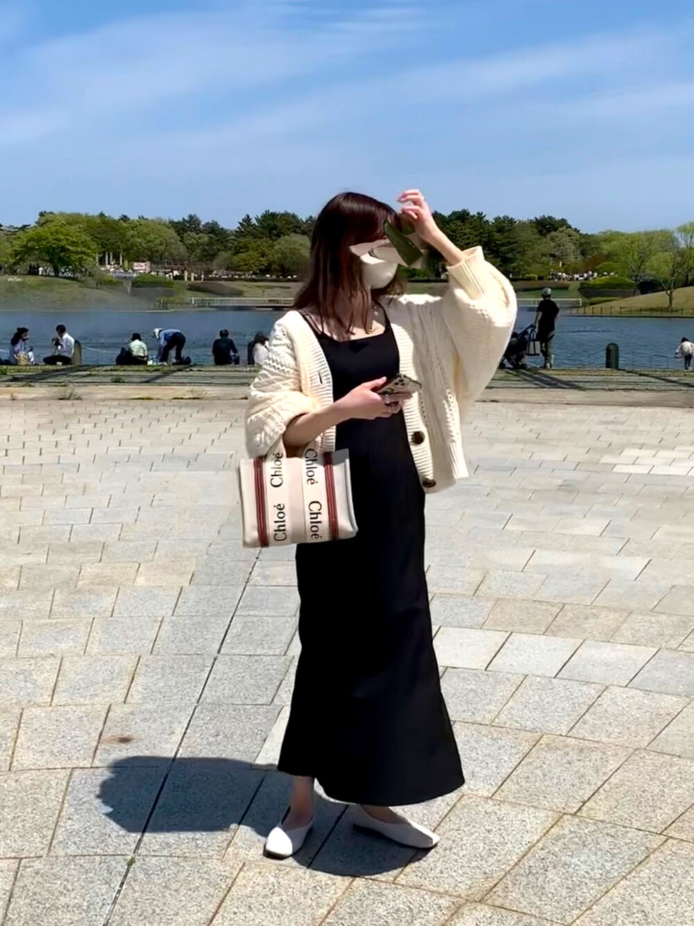 ブラック系のワンピース、ブラック系のキャミソール、ブラウン系のハンドバッグを着用したレディースの春コーディネートの1枚目の写真