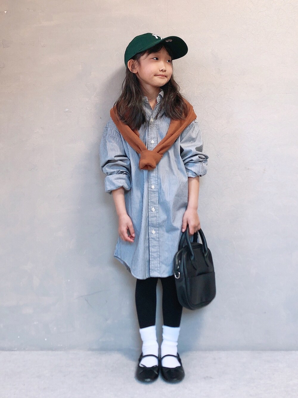 イエロー系のニット/セーター、ブラック系のボストンバッグ、ブラック系のバレエシューズを着用したキッズの春コーディネートの1枚目の写真