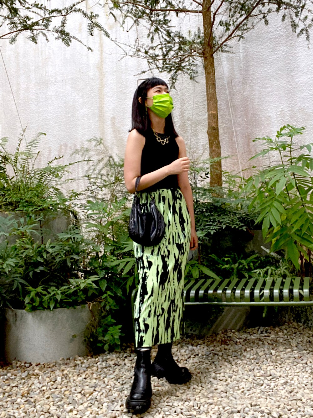 グリーン系のスカート、ブラック系のショルダーバッグ、ブラック系のブーツを着用したレディースの夏コーディネートの1枚目の写真