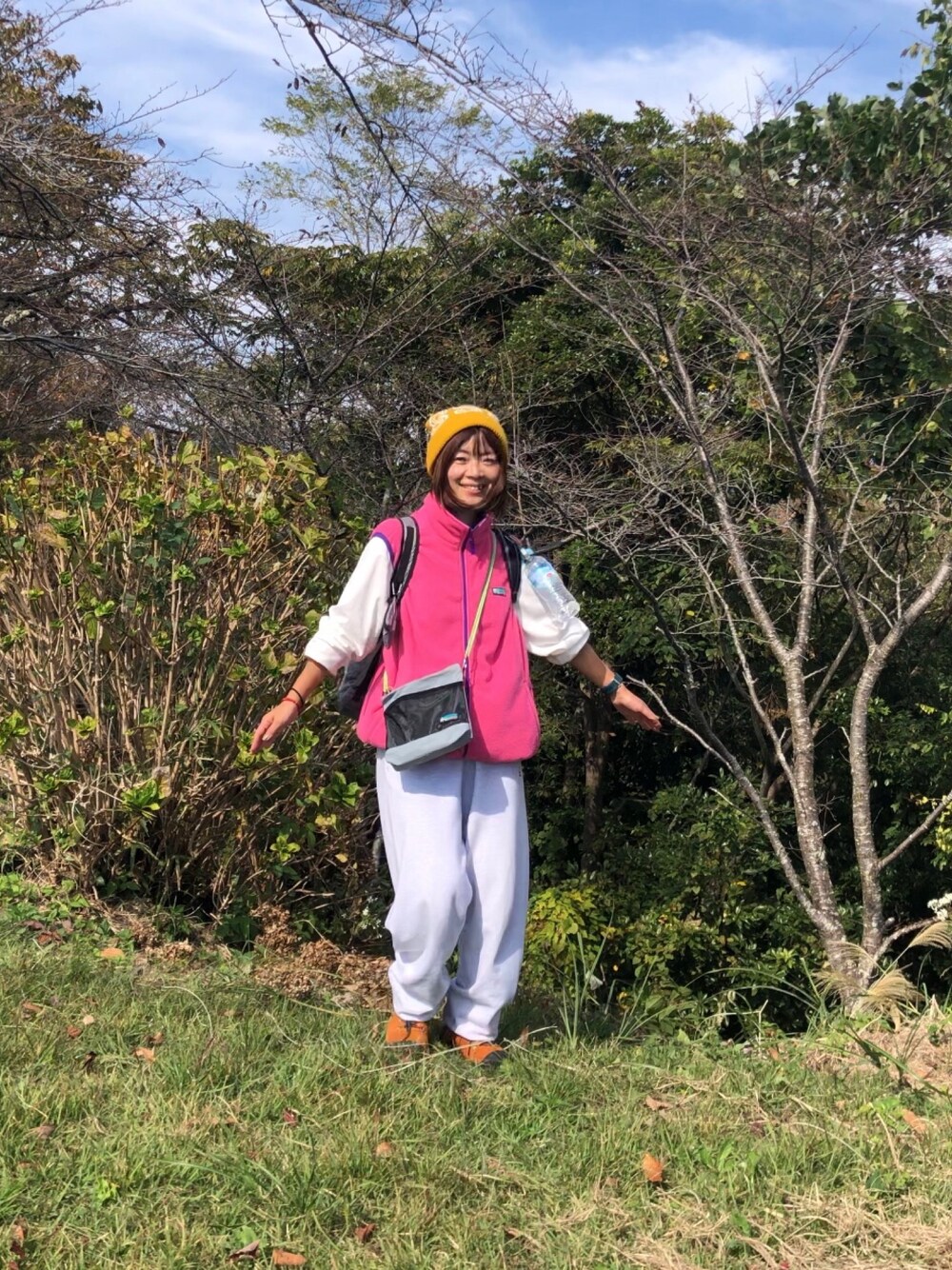 グレー系のスウェットパンツ、パープル系のベスト、ブルー系のショルダーバッグを着用したレディースの秋コーディネートの1枚目の写真
