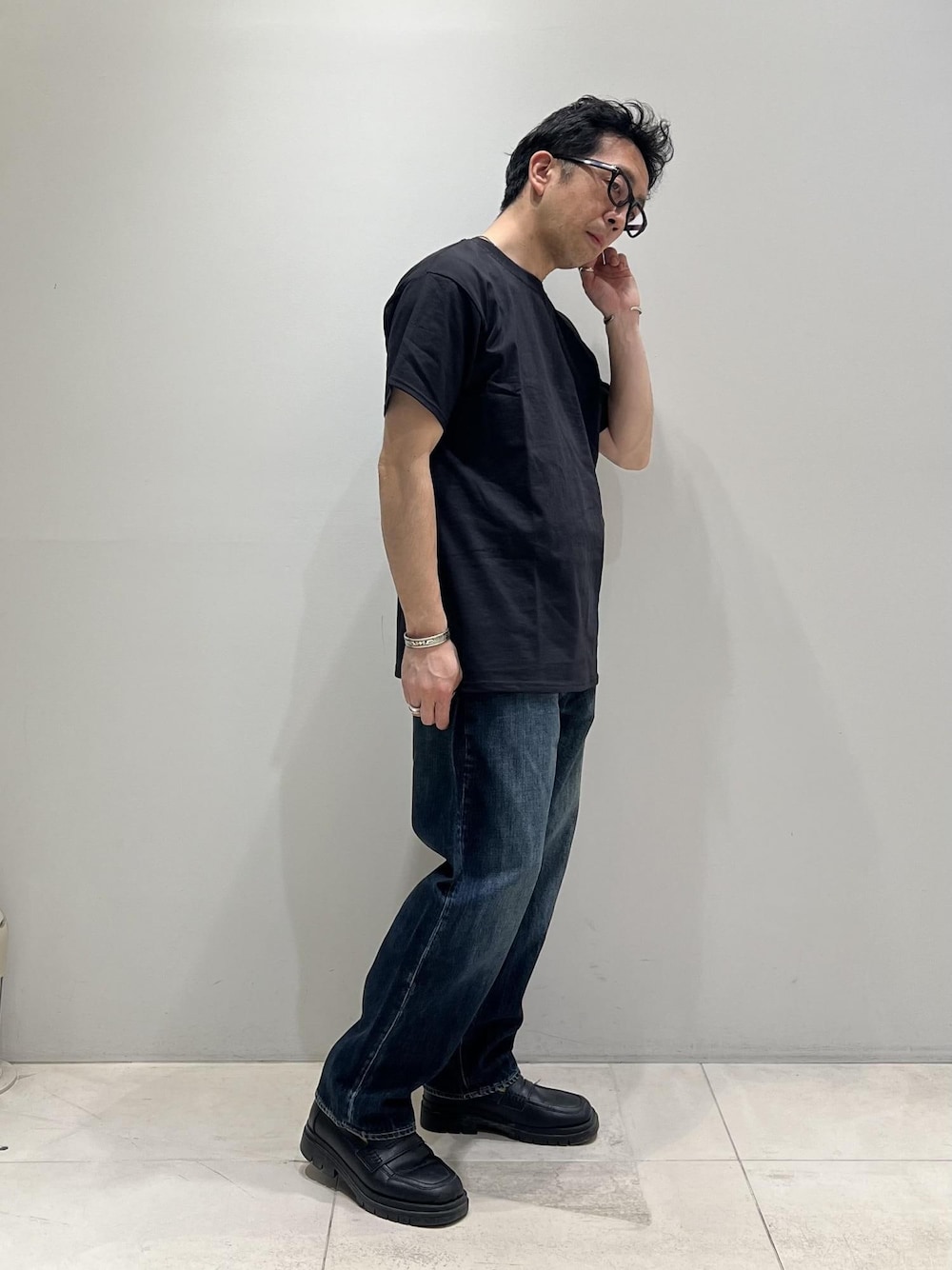 ブルー系のデニムパンツ、ホワイト系のシャツ/ブラウス、ブラック系のTシャツ/カットソーを着用したメンズの春コーディネートの1枚目の写真