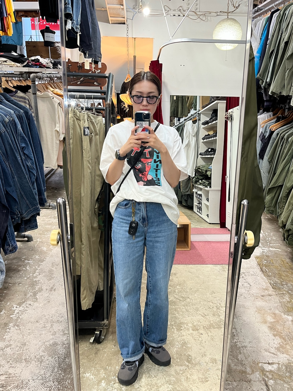 ブラック系のショルダーバッグ、ホワイト系のTシャツ/カットソー、ブルー系のデニムパンツを着用したレディースの秋コーディネートの1枚目の写真