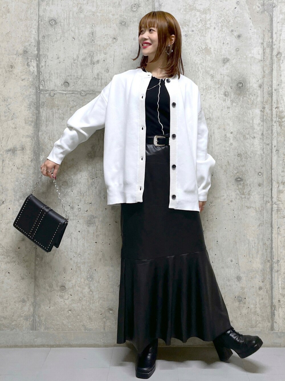 ブラック系のショルダーバッグ、ブラック系のブーツ、ブラック系のスカートを着用したレディースの秋コーディネートの1枚目の写真