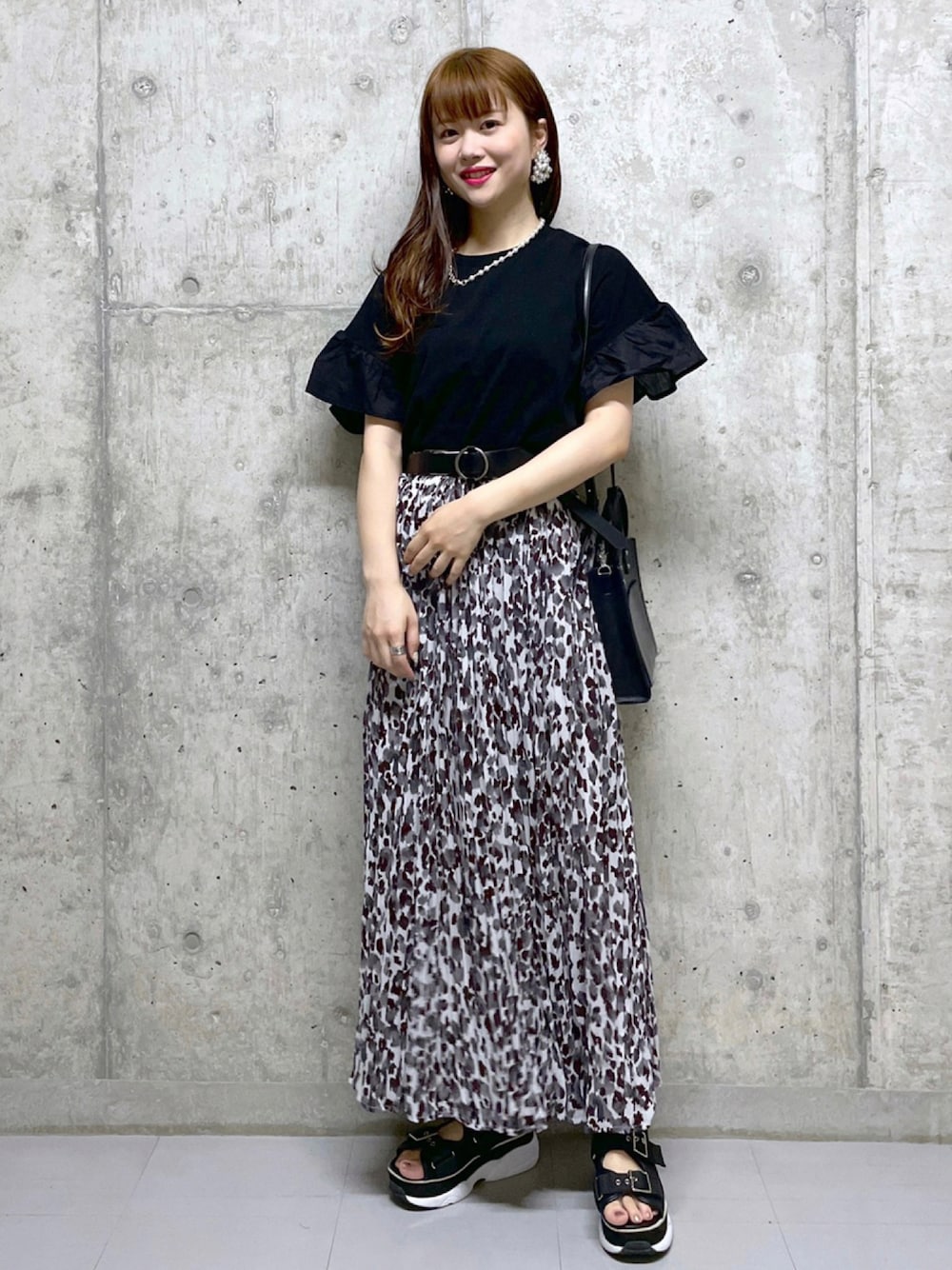 ベージュ系のスカート、ブラック系のサンダル、ブラック系のショルダーバッグを着用したレディースの夏コーディネートの1枚目の写真