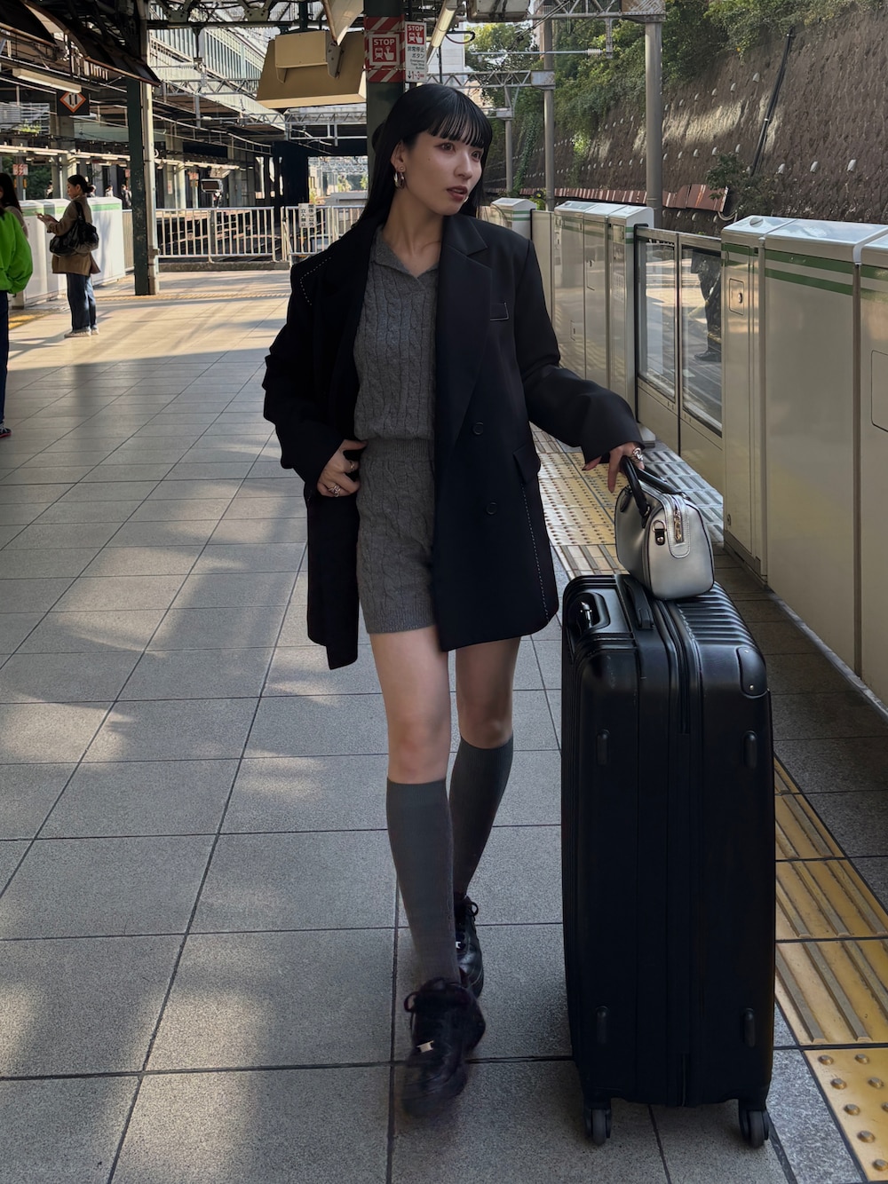 ブラック系のテーラードジャケット、グレー系のニット/セーター、ブラック系のスニーカーを着用したレディースの秋コーディネートの1枚目の写真