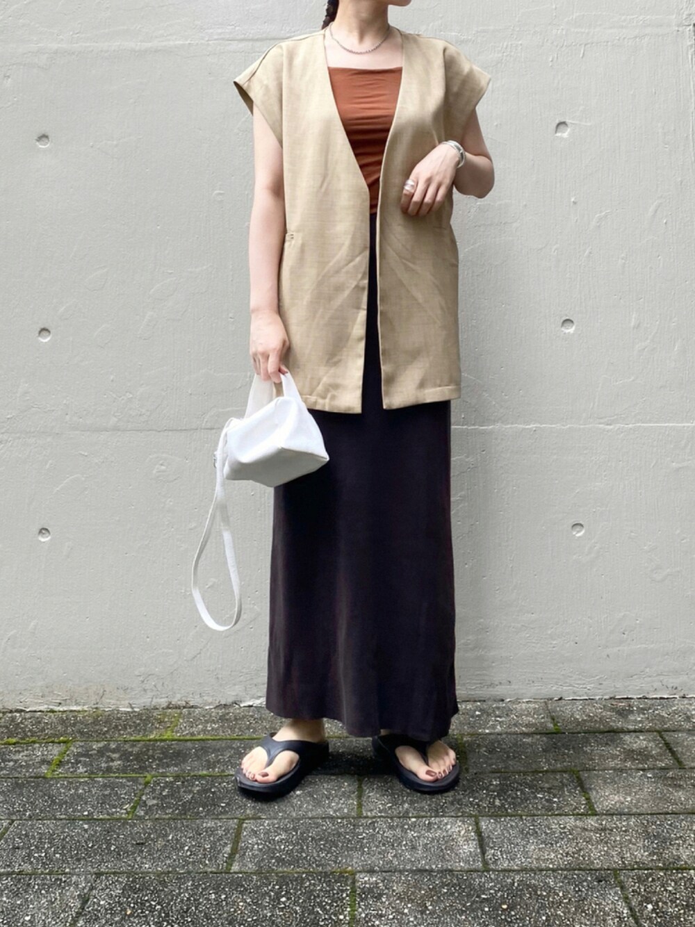 イエロー系のノーカラージャケット、ブラウン系のスカート、ホワイト系のバッグを着用したレディースの夏コーディネートの1枚目の写真