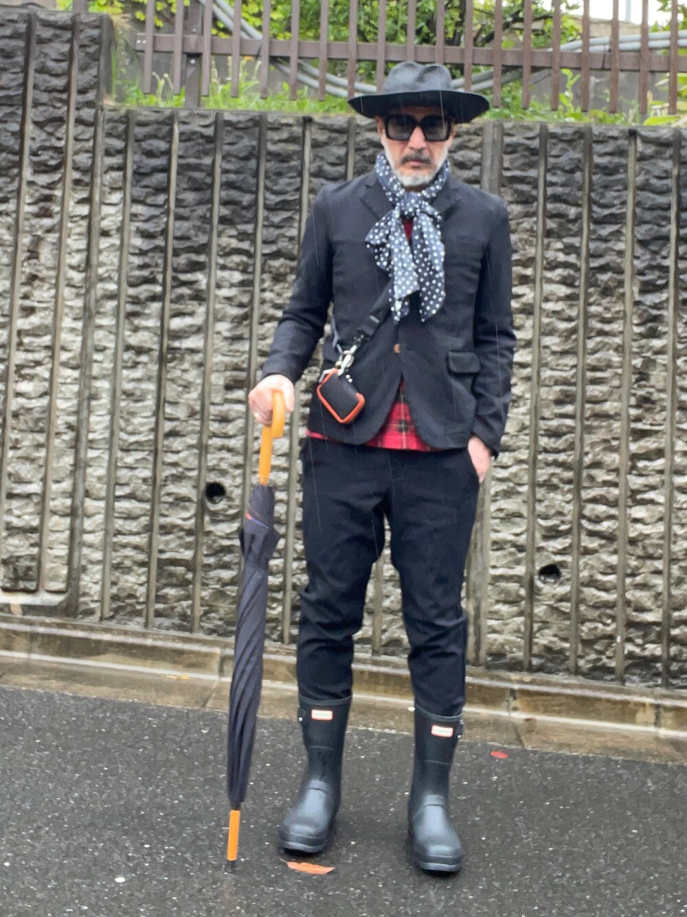 ブラック系のレインシューズ、ブラック系のハット、ブラック系のメガネを着用したメンズの春コーディネートの1枚目の写真