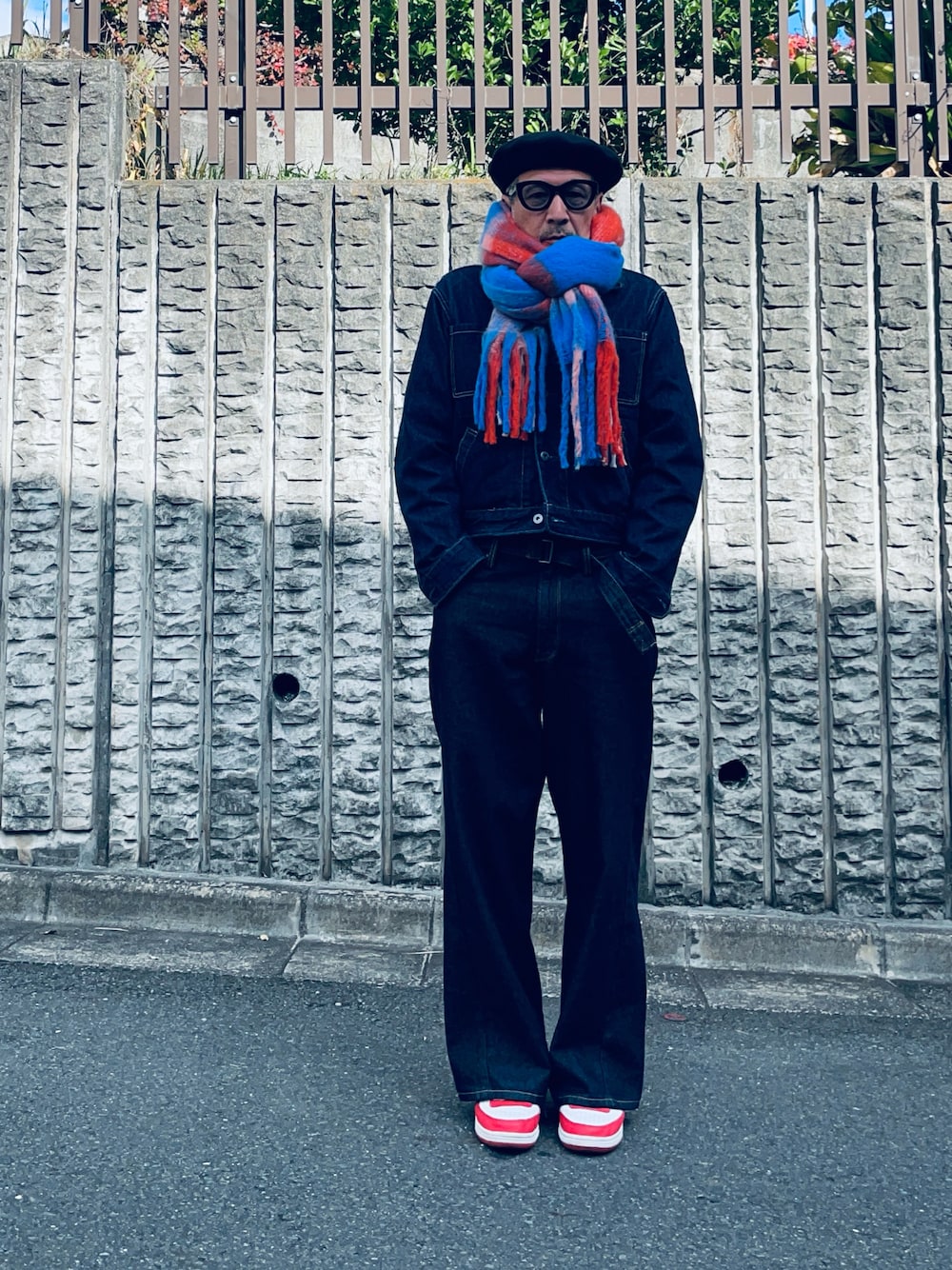 ブルー系のデニムパンツ、ホワイト系のスニーカー、その他のマフラーを着用したメンズの秋コーディネートの1枚目の写真