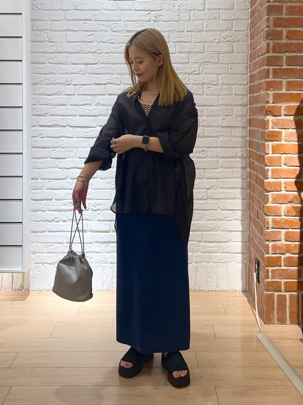 ブルー系のスカート、ブラック系のサンダル、ホワイト系のTシャツ/カットソーを着用したレディースの夏コーディネートの1枚目の写真