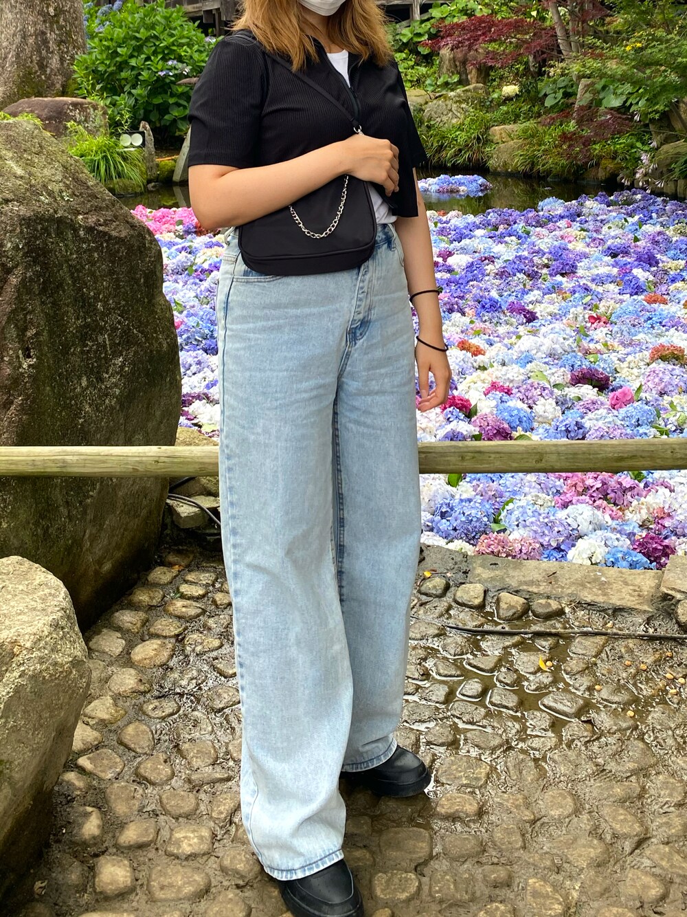 ブルー系のデニムパンツ、ブラック系のスニーカー、ブラック系のトップスを着用したレディースの夏コーディネートの1枚目の写真