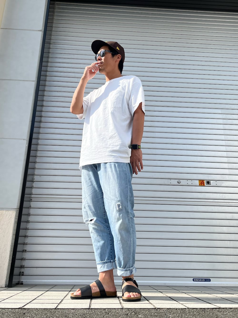 ホワイト系のTシャツ/カットソー、ブルー系のデニムパンツ、ブラック系のサンダルを着用したメンズの夏コーディネートの1枚目の写真