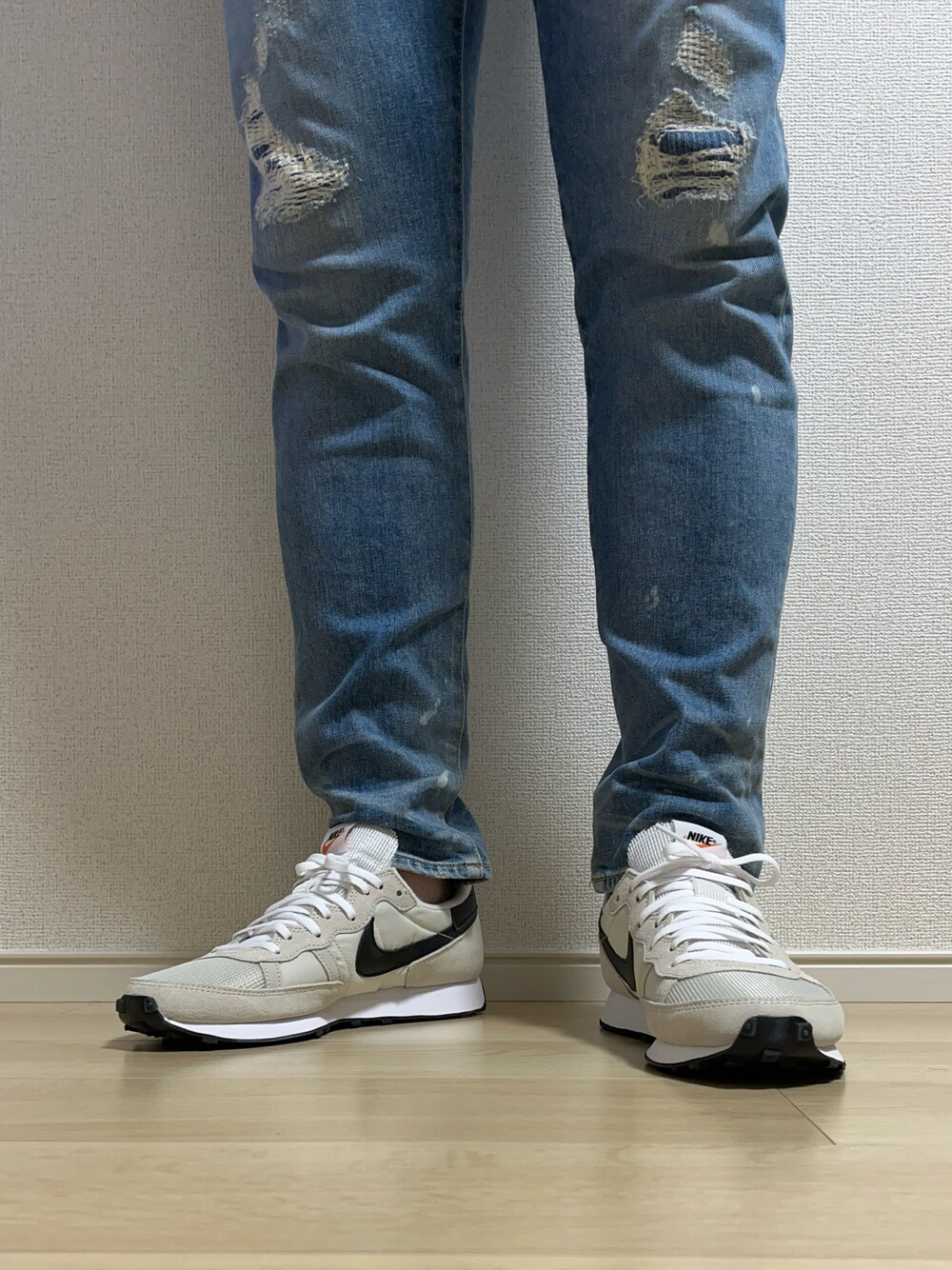 ブルー系のデニムパンツ、ベージュ系のスニーカーを着用したメンズの春コーディネートの1枚目の写真